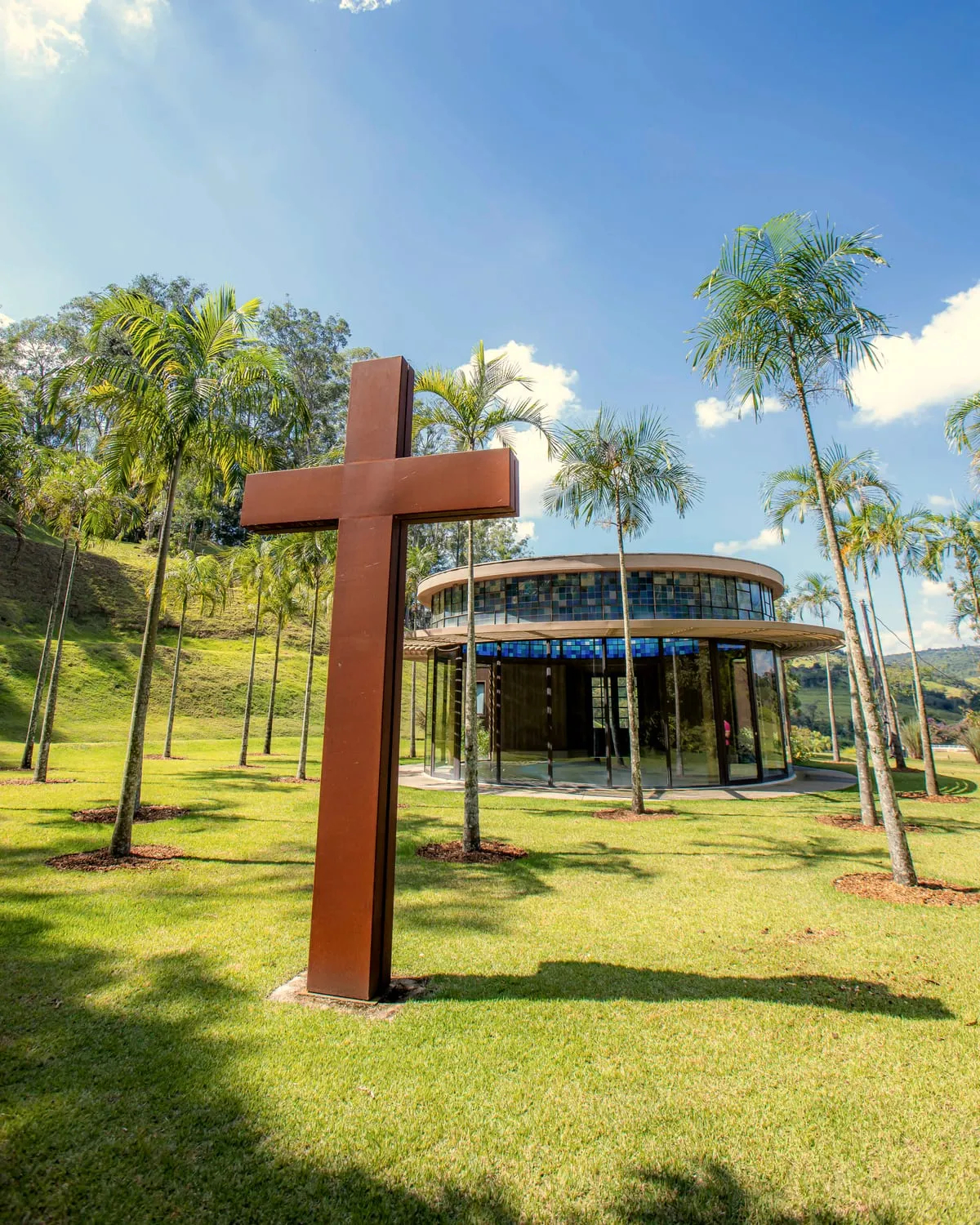 A capela ecumênica, um templo redondo de vidro com uma cruz de aço, entre palmeiras