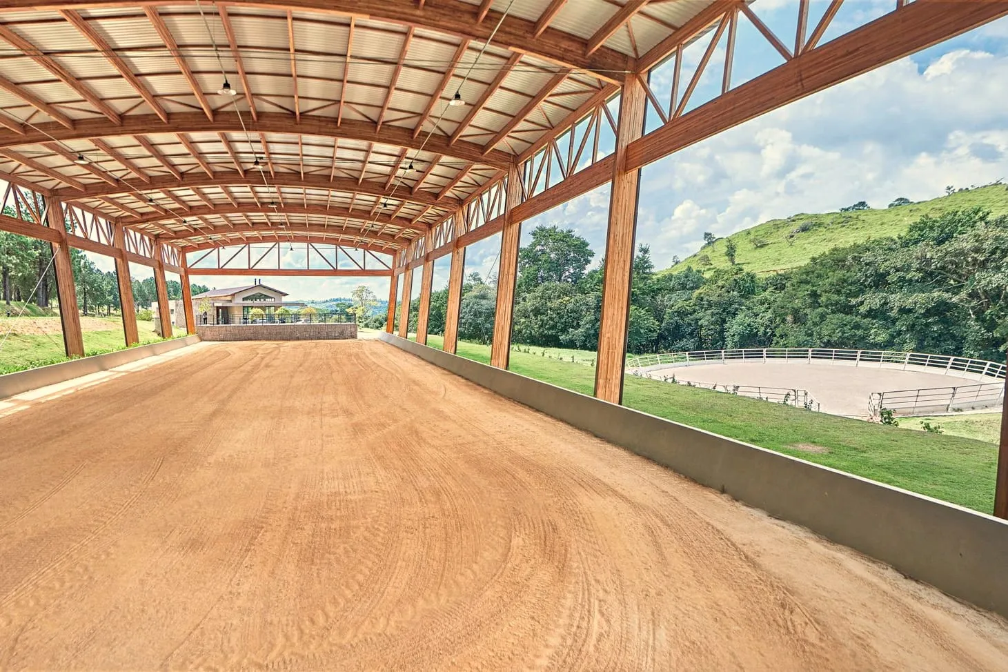 O interior da pista coberta, com o telhado apoiado em tesouras de madeira e o vale enquadrado pelas laterais abertas