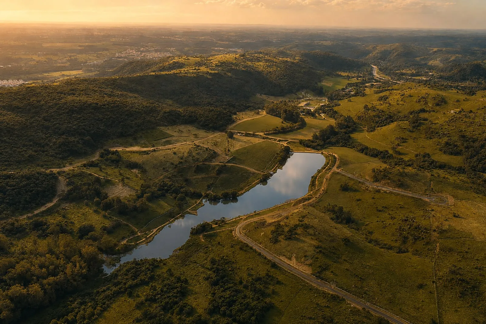 O vale do Haras La Estancia ao fim da tarde, com o lago ao centro e o horizonte de Campinas ao fundo.