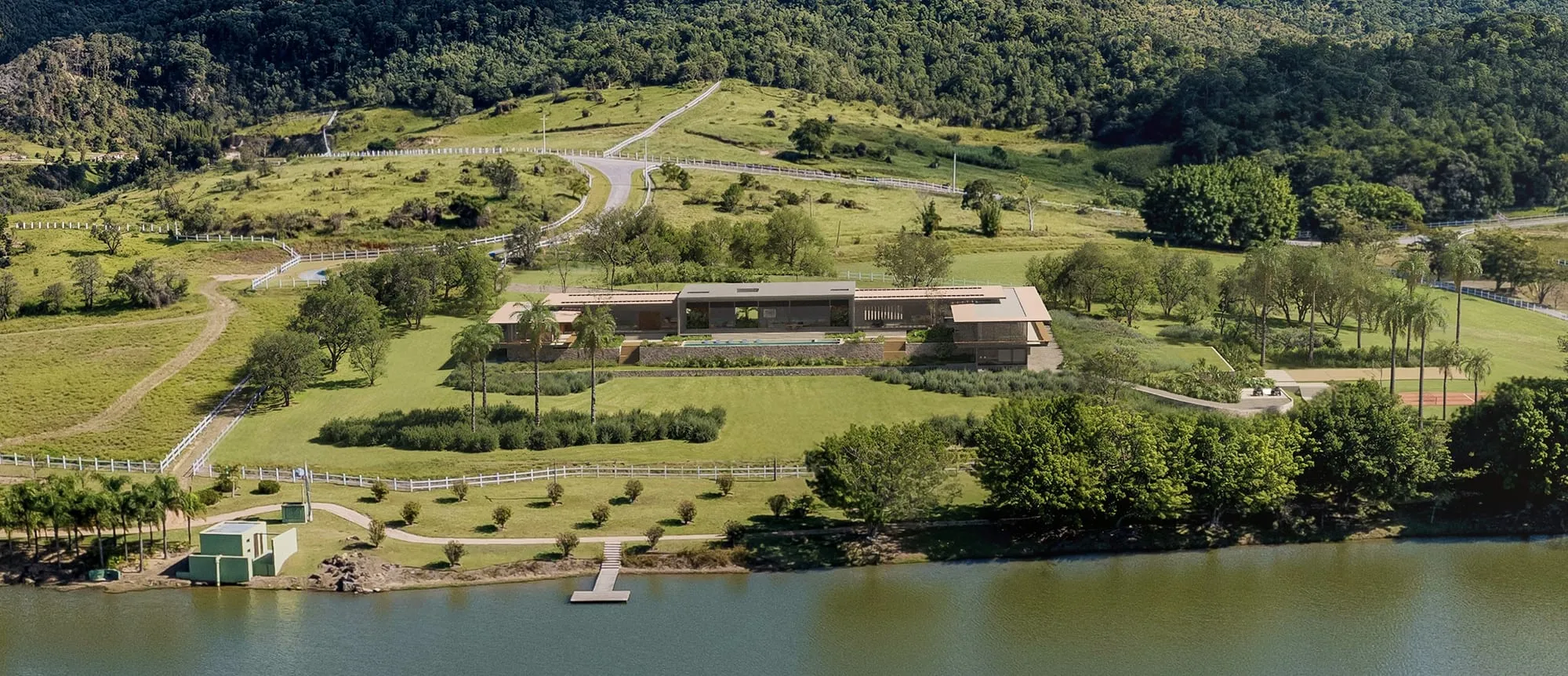 Vista aérea da casa implantada na estância, com o lago à frente e a mata nas encostas